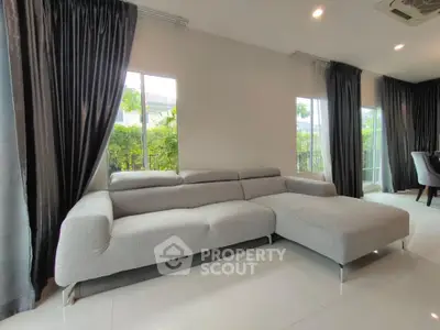 Spacious modern living room with elegant grey sofa and large windows.