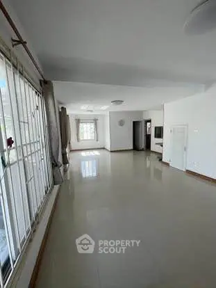 Spacious living room with large windows and natural light, perfect for family gatherings.