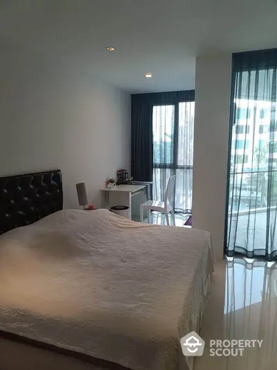 Modern bedroom with large windows and balcony access in a stylish apartment.