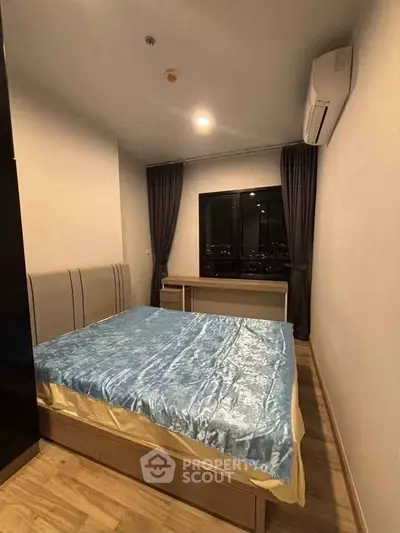 Cozy bedroom with modern furnishings and city view, featuring a comfortable bed and air conditioning.
