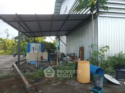Industrial property exterior with covered storage area and equipment.