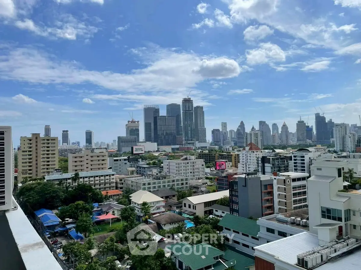 Stunning cityscape view from a high-rise balcony showcasing urban skyline and blue sky.