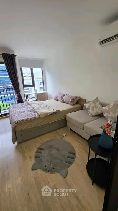Cozy bedroom with modern decor and city view, featuring a comfortable bed and stylish sofa.