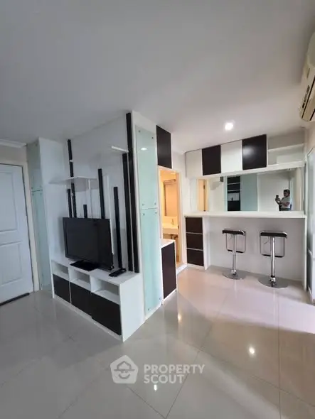 Modern open-plan living area with sleek TV unit and breakfast bar