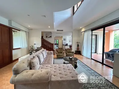 Spacious living room with elegant decor and large windows opening to a balcony.