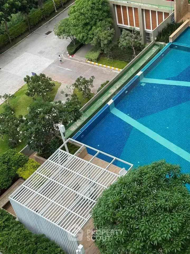 Stunning aerial view of modern swimming pool surrounded by lush greenery in a luxury residential complex.