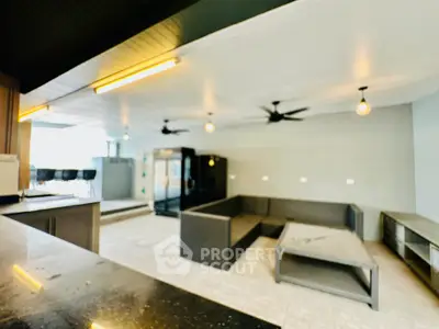 Modern indoor lounge area with stylish seating and ceiling fans, perfect for relaxation and entertainment.