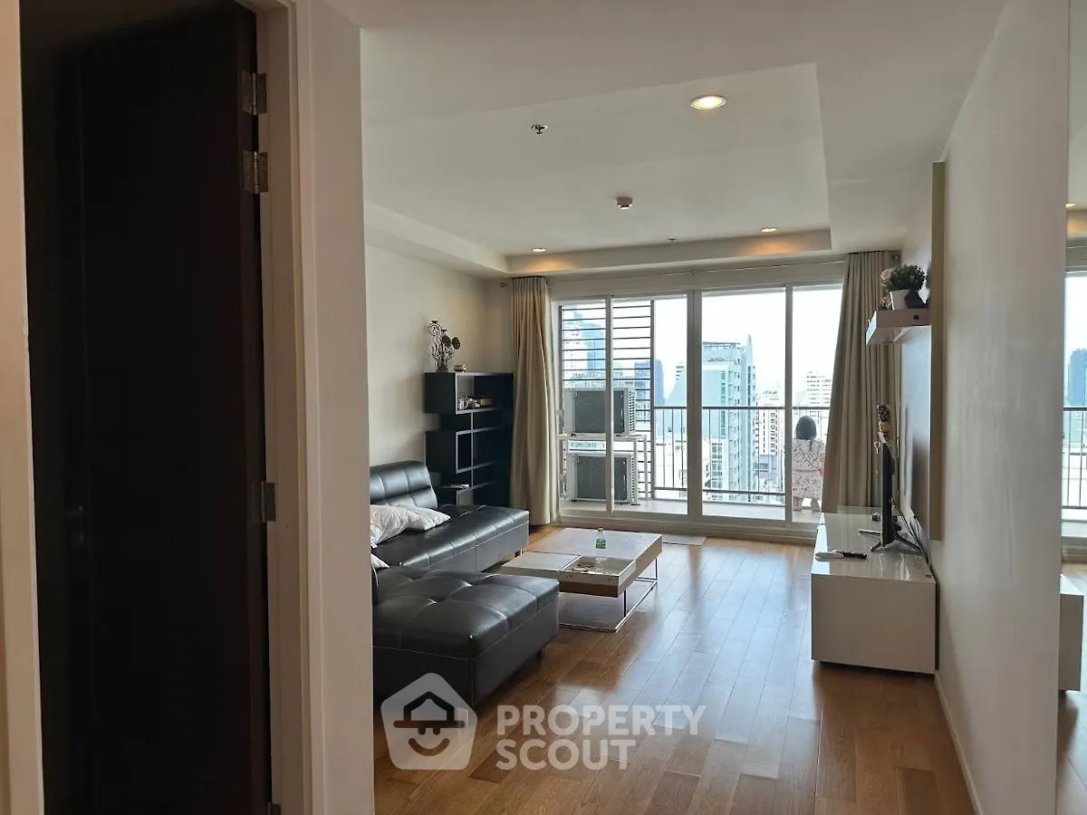 Modern living room with city view, featuring sleek furniture and large windows for natural light.