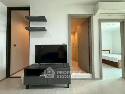 Modern apartment interior with TV, shelves, and visible bedroom and bathroom.