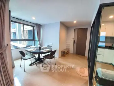 Modern dining area with large windows and open kitchen in a stylish apartment.