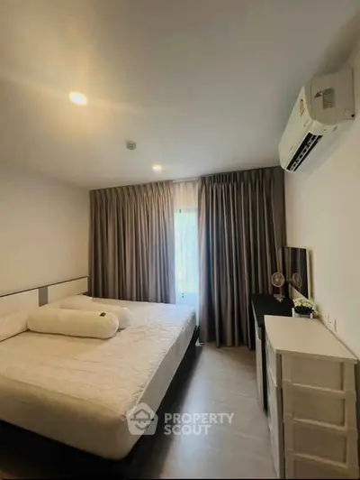 Cozy bedroom with modern decor and air conditioning, featuring a comfortable bed and elegant curtains.