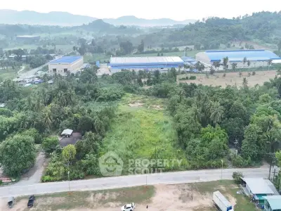 Expansive land plot with lush greenery and industrial surroundings, ideal for development opportunities.
