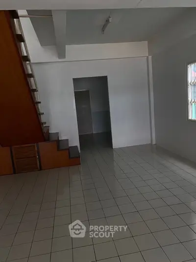 Spacious interior with tiled flooring and wooden staircase, ideal for customization.