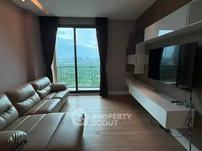 Modern living room with large window offering stunning city view, featuring sleek furniture and stylish decor.