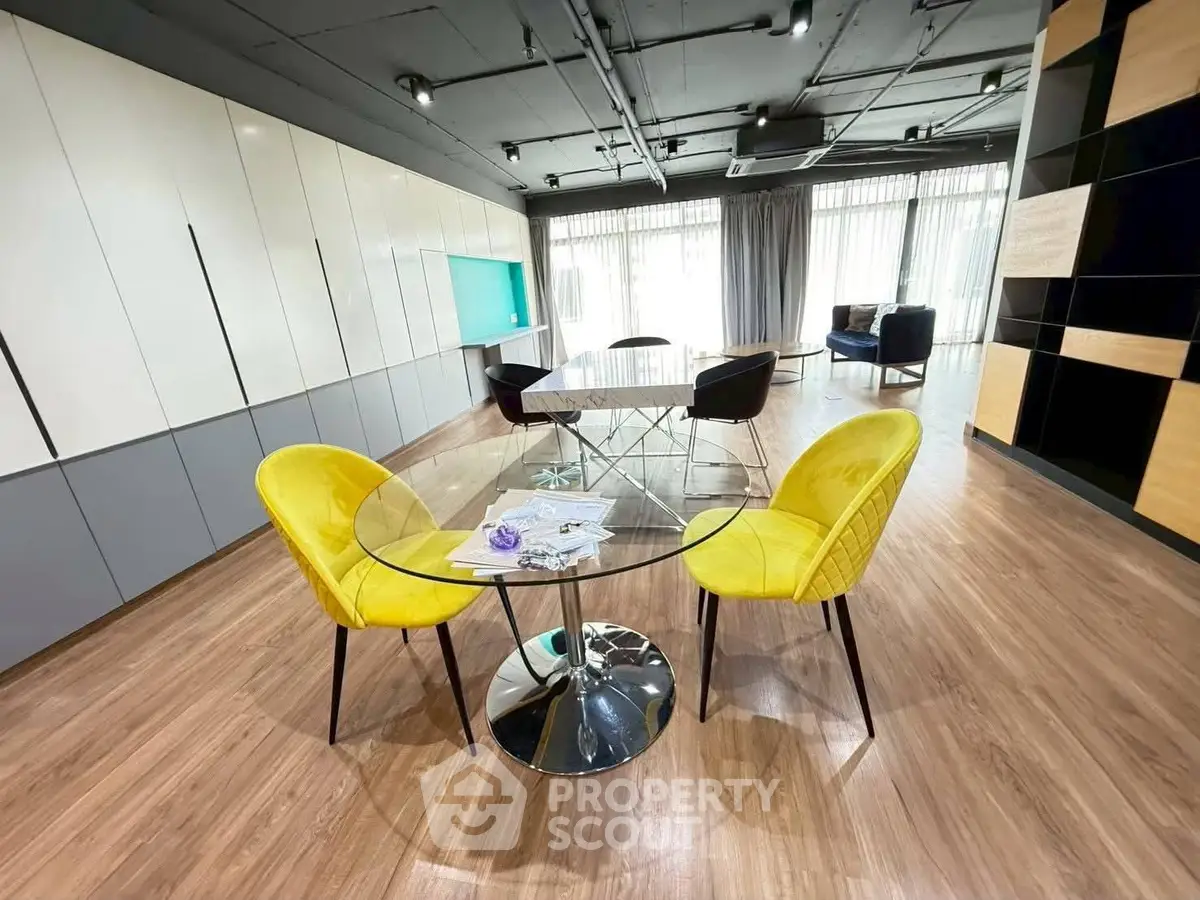 Modern living room with stylish furniture and open layout, featuring vibrant yellow chairs and sleek wooden flooring.
