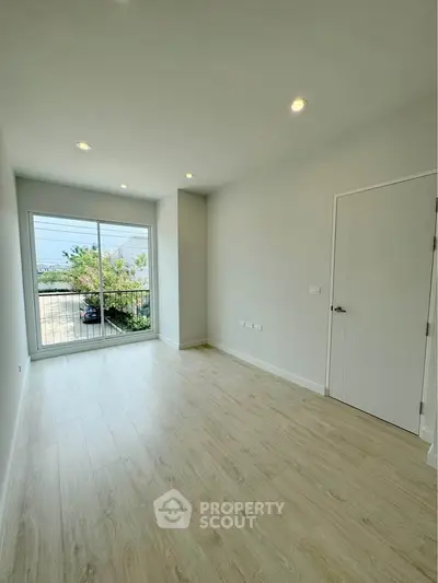 Spacious empty room with large window and balcony view, perfect for customization.