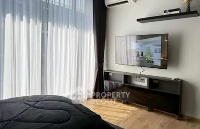 Modern bedroom with sleek TV setup and large window for natural light.