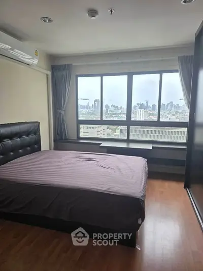 Spacious bedroom with city view, featuring large windows and modern furnishings.