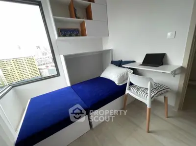 Modern compact bedroom with blue bed, wall shelves, and study desk in urban apartment.