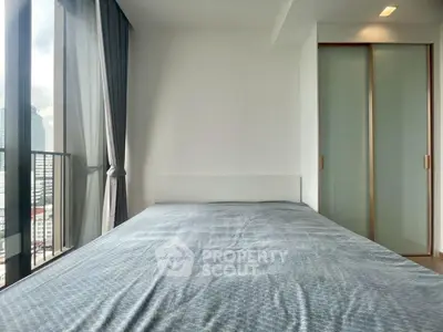 Modern bedroom with large window and city view, featuring a sleek design and ample natural light.