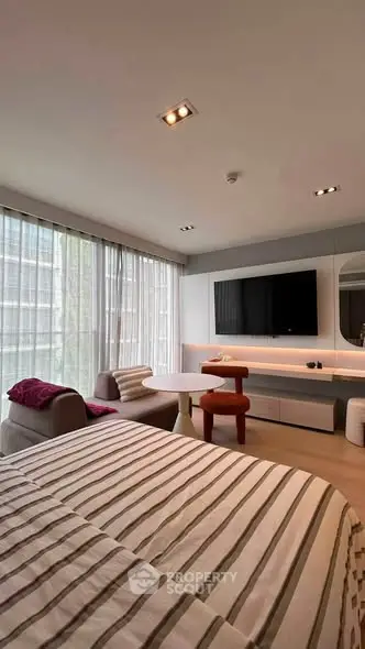 Modern bedroom with stylish decor, large windows, and a cozy seating area, perfect for relaxation and comfort.
