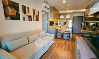 Modern living room with stylish decor and open kitchen layout, featuring cozy seating and contemporary lighting.