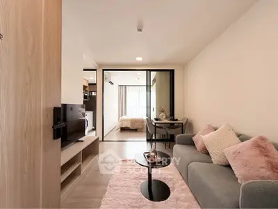 Modern open-plan living room with cozy sofa and stylish decor leading to a bright bedroom.