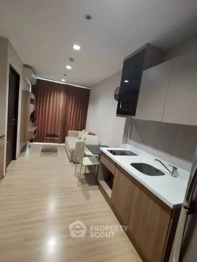 Modern open-layout kitchen and living room with sleek design and wooden flooring.