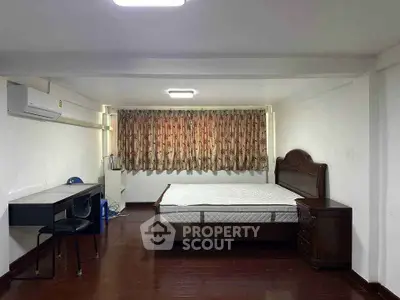 Spacious bedroom with wooden flooring and elegant furniture