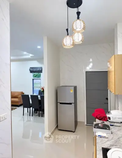 Modern kitchen with sleek appliances and open layout leading to dining area.