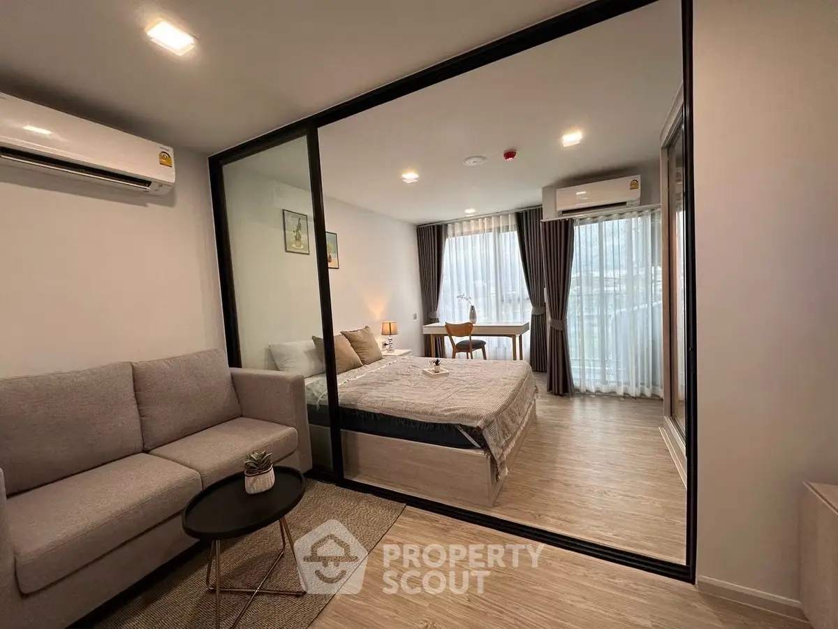 Modern studio apartment with glass partition, cozy living area, and natural light.