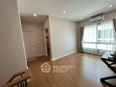 Spacious living room with wooden flooring and large windows in modern apartment.