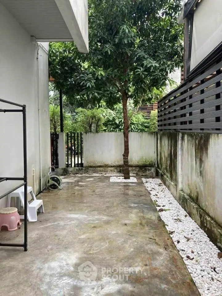 Charming outdoor space with tree and modern fence, perfect for relaxation and gardening.