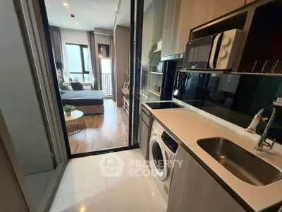 Modern apartment with sleek kitchen and cozy bedroom, featuring a washing machine and stylish decor.