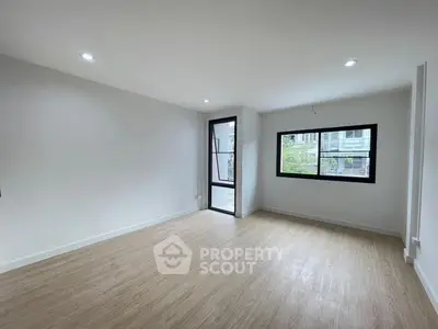 Spacious empty room with wooden flooring and large windows, ideal for customization.