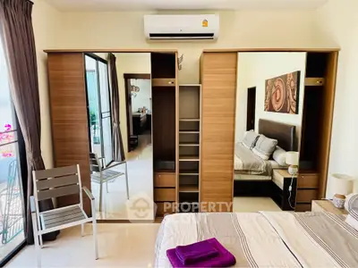 Modern bedroom with mirrored wardrobe and balcony access in a stylish apartment.