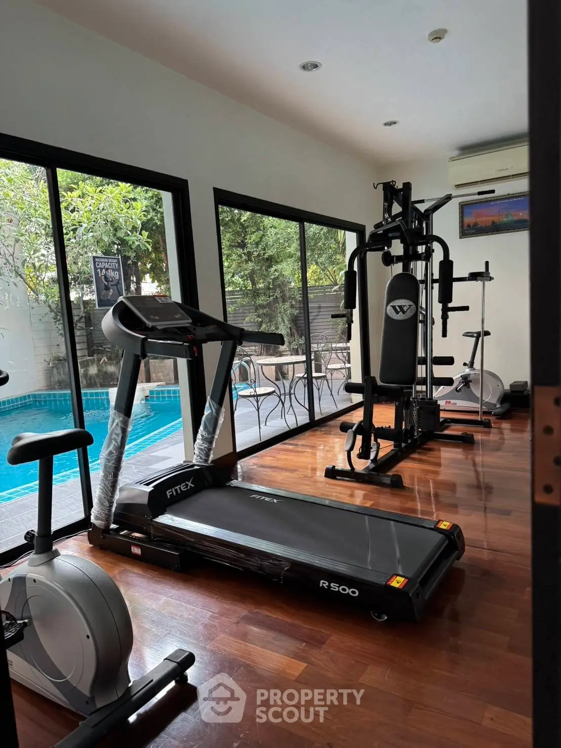 Modern home gym with pool view and fitness equipment
