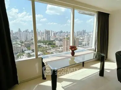 Stunning city view from modern apartment with floor-to-ceiling windows and elegant glass table.