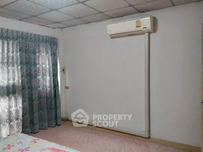 Spacious bedroom with air conditioning and floral curtains, perfect for comfort and relaxation.