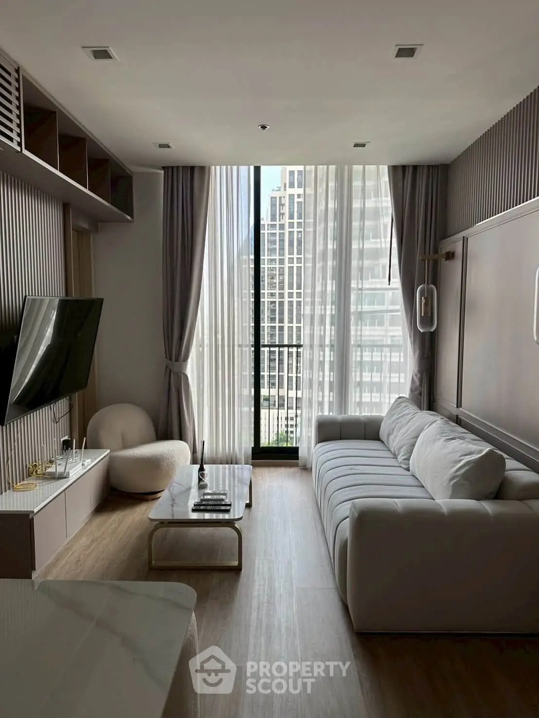 Modern living room with floor-to-ceiling windows and city view, featuring sleek furniture and elegant decor.