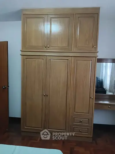 Spacious wooden wardrobe in a cozy bedroom setting with parquet flooring.