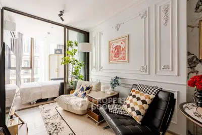 Luxurious living room with elegant decor and view into a stylish bedroom, featuring chic furniture and wall art.
