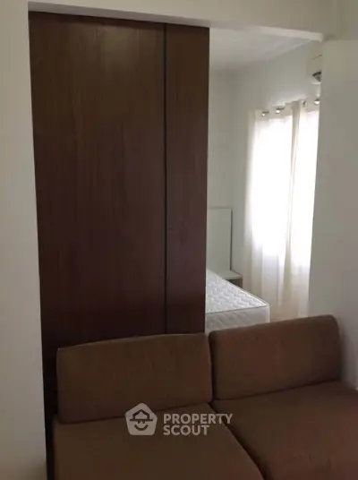 Cozy bedroom with brown sofa and natural light through curtains