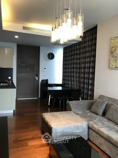 Modern living room with elegant chandelier and cozy sectional sofa in a stylish apartment.