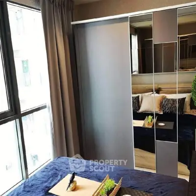 Modern bedroom with mirrored wardrobe and large window for natural light.