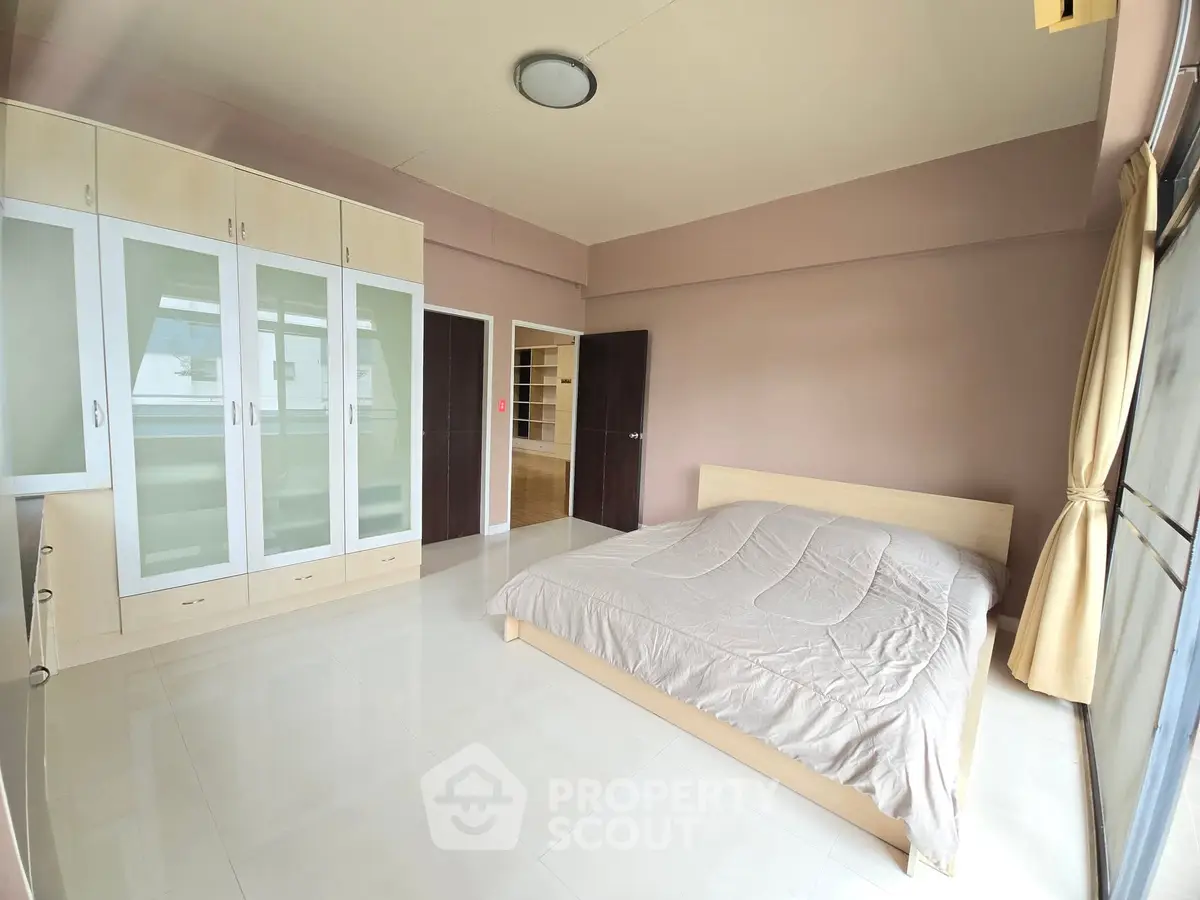 Spacious bedroom with modern built-in wardrobe and large window for natural light.