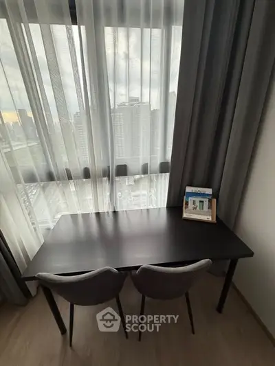 Modern study area with city view, featuring sleek desk and chairs by large window.