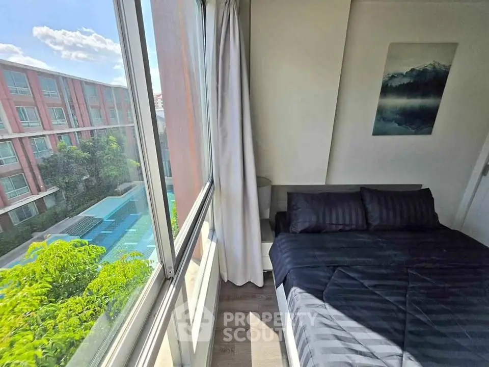 Cozy bedroom with large window offering a stunning pool view in modern apartment.