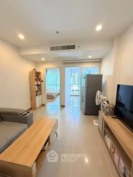 Modern living room with sleek furniture and open view to bedroom, featuring a cozy ambiance and natural light.