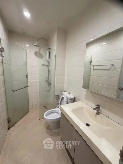 Modern bathroom with glass shower, sleek vanity, and neutral tiles